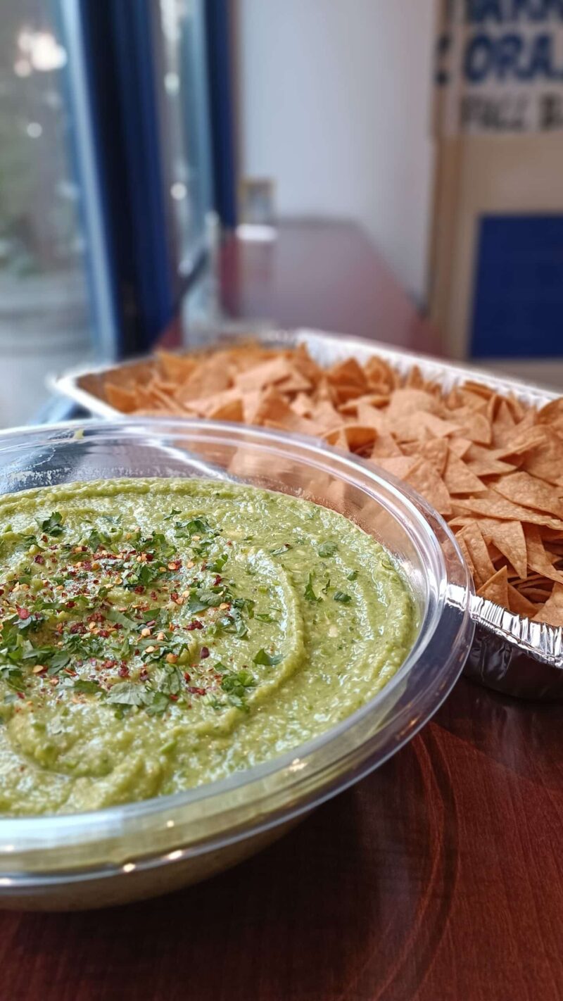 A bowl of guacamole with a tray of chips. Perfect for dipping and snacking.