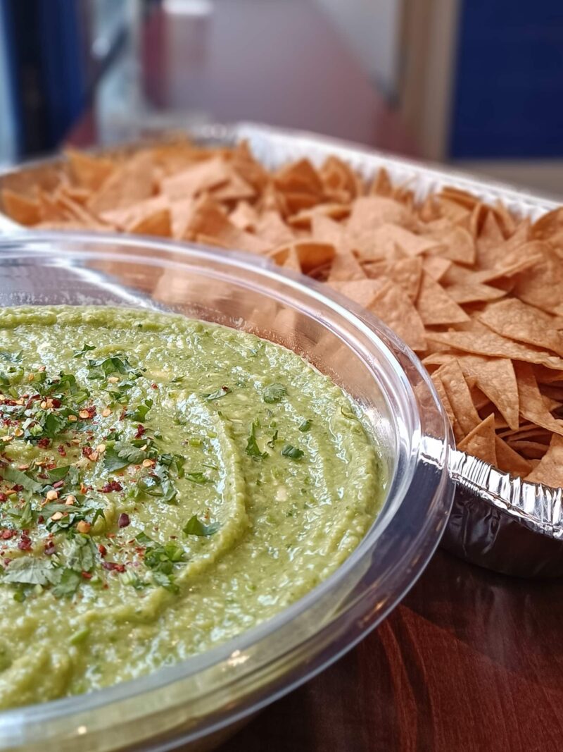 A tray with guacamole dip and crispy chips, ready to be devoured. Perfect for parties and gatherings.