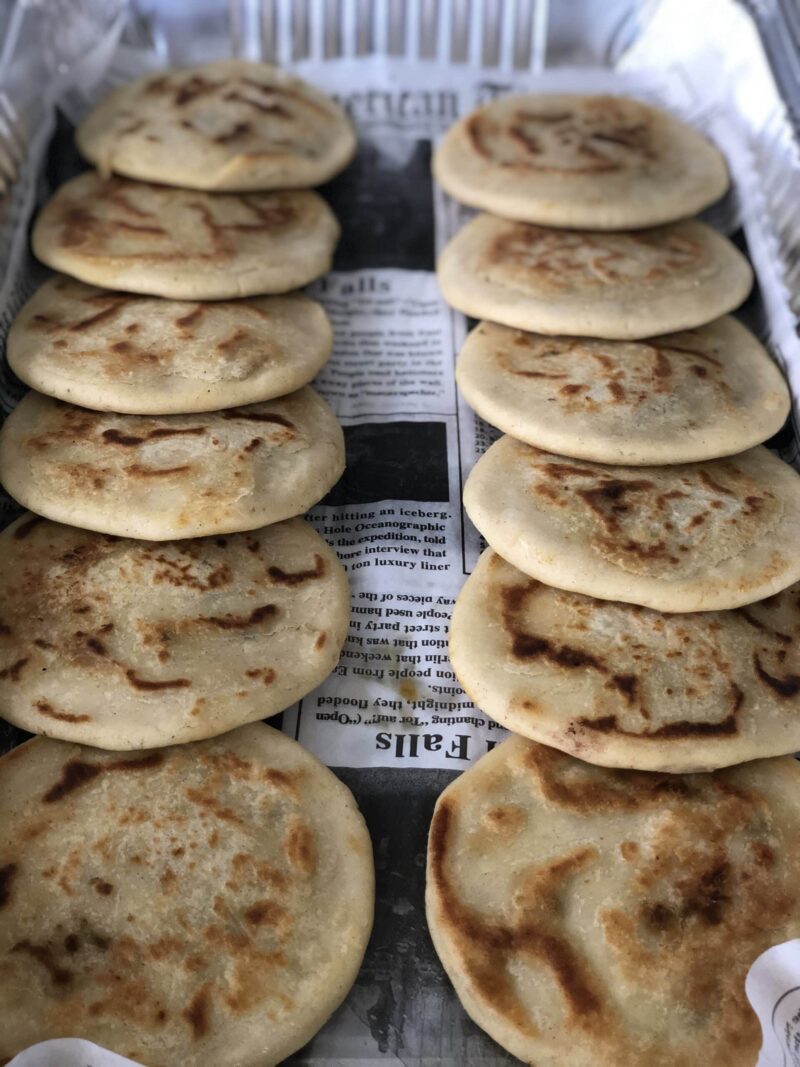 Pupusas tray in the chicharron pork flavor, featuring corn dough and serve with salsa, curtido and pickled red onions.