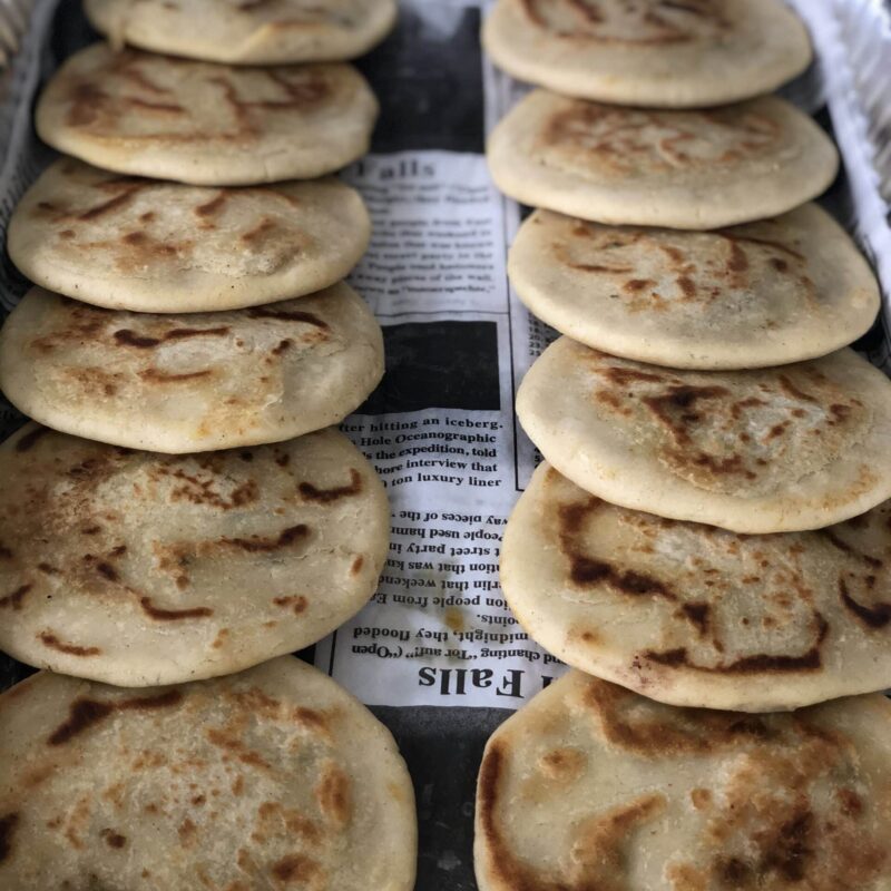 Pupusas tray in the chicharron pork flavor, featuring corn dough and serve with salsa, curtido and pickled red onions.