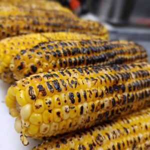 Delectable street corn from El Merkury, adorned with tantalizing toppings on a tray.