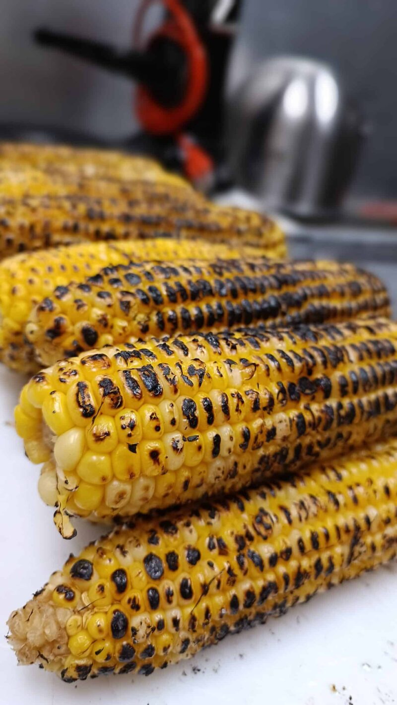 Delectable street corn from El Merkury, adorned with tantalizing toppings on a tray.