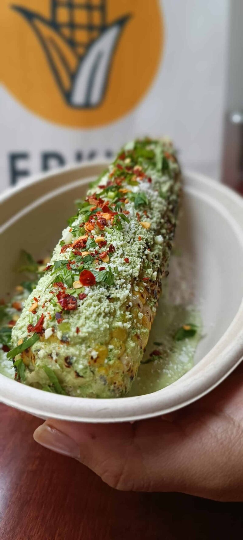 A tray featuring El Merkury's street corn elote loco, adorned with flavorful toppings for a delightful treat.