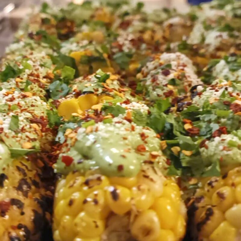 A tray showcasing El Merkury's street corn, adorned with flavorful toppings for a delightful treat.