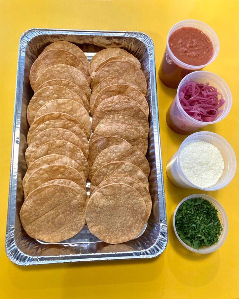 Tostada bar in a yellow table, paired with salsa, curtido, cotija cheese and cilantro