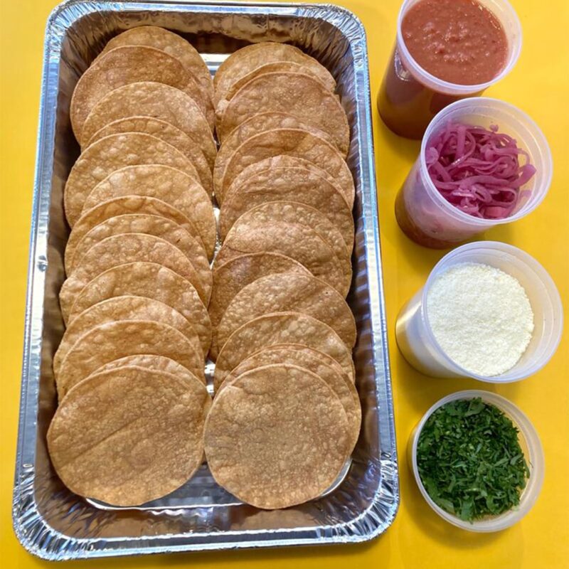 Tostada bar in a yellow table, paired with salsa, curtido, cotija cheese and cilantro